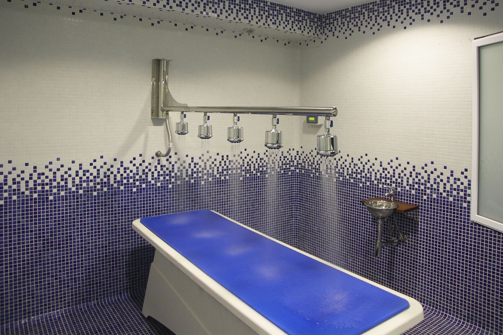 Ducha Vichy bitérmica con brazo artículado y 5 rociadores en pared de mosaico